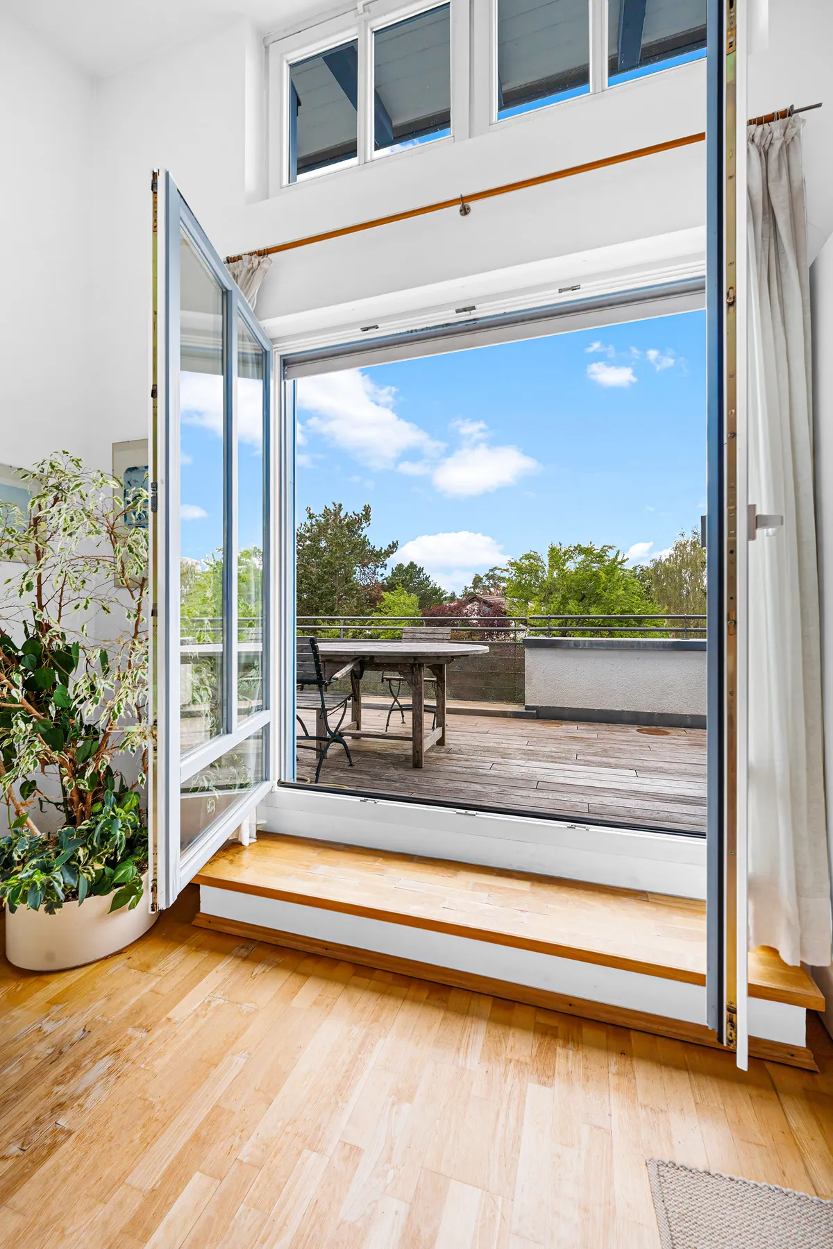 Blick vom Wohnbereich durch die offene Terrassentür auf die Dachterrasse