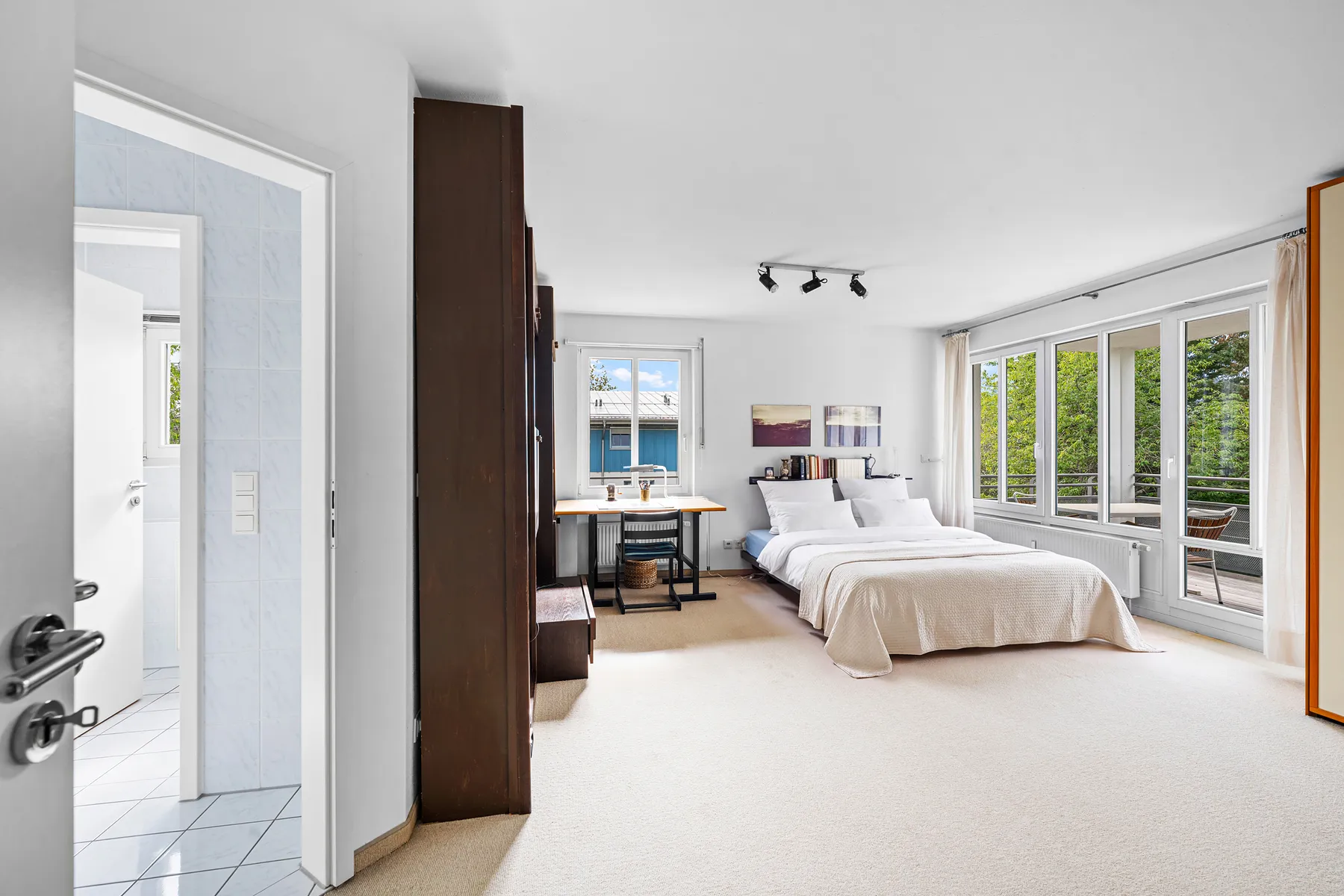 Schlafzimmer mit Tür zum Bad en suite und zum überdachten Balkon