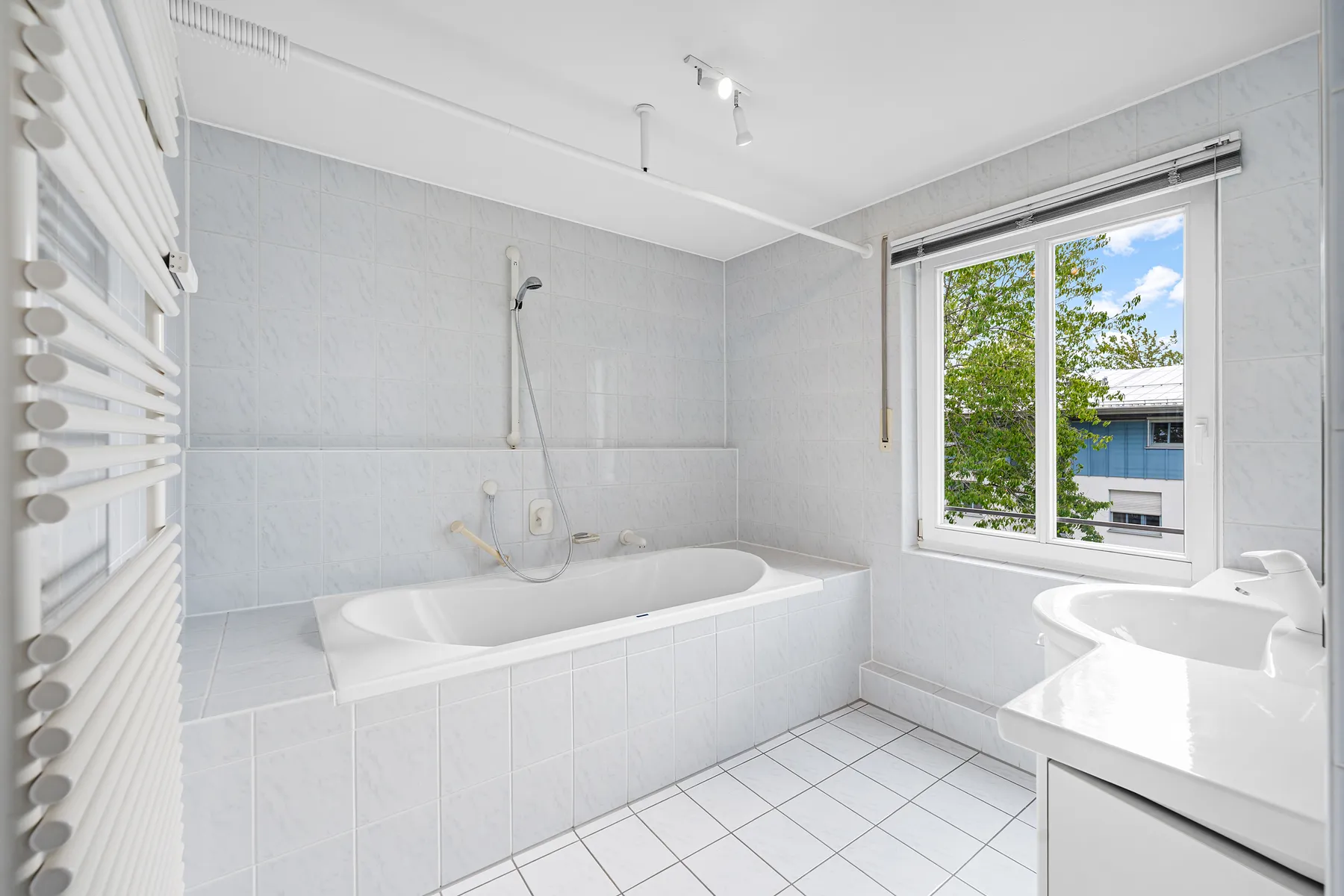 Bad en suite mit Badewanne und Fenster, raumhoch gefliest