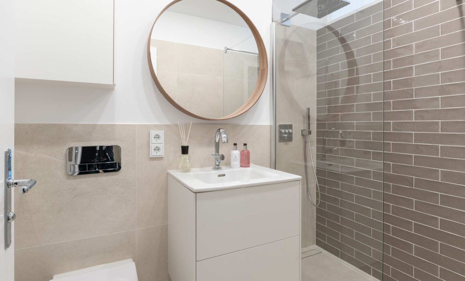 Badezimmer mit Regendusche und rundem Spiegel